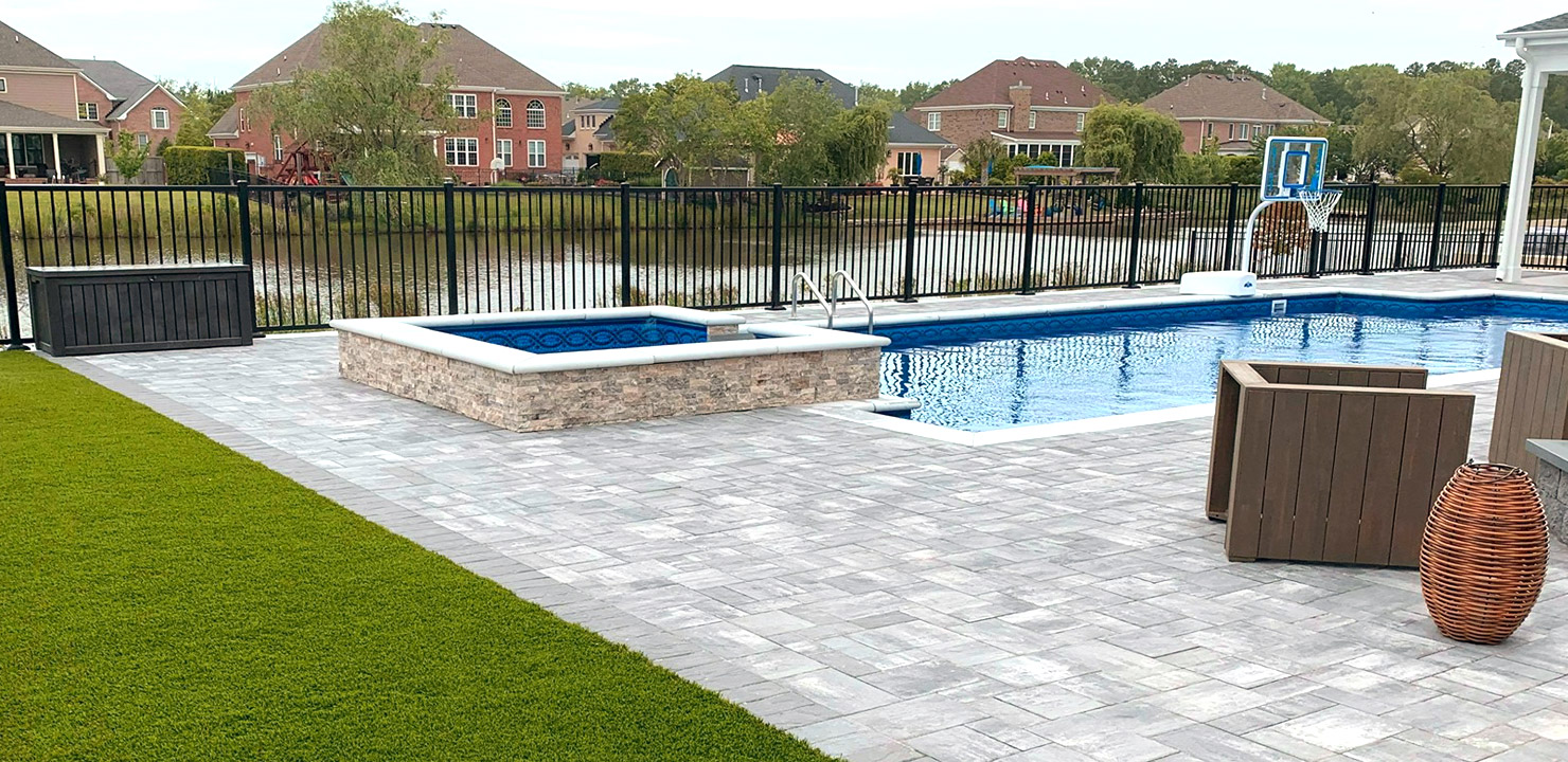 Backyard with a pool and artificial turf outside of the hardscaping
